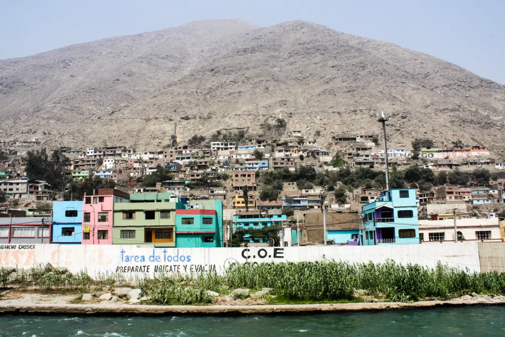 Colorful buildings and homes dot the view from the Rímac River bank in rural Chosica, Peru. 