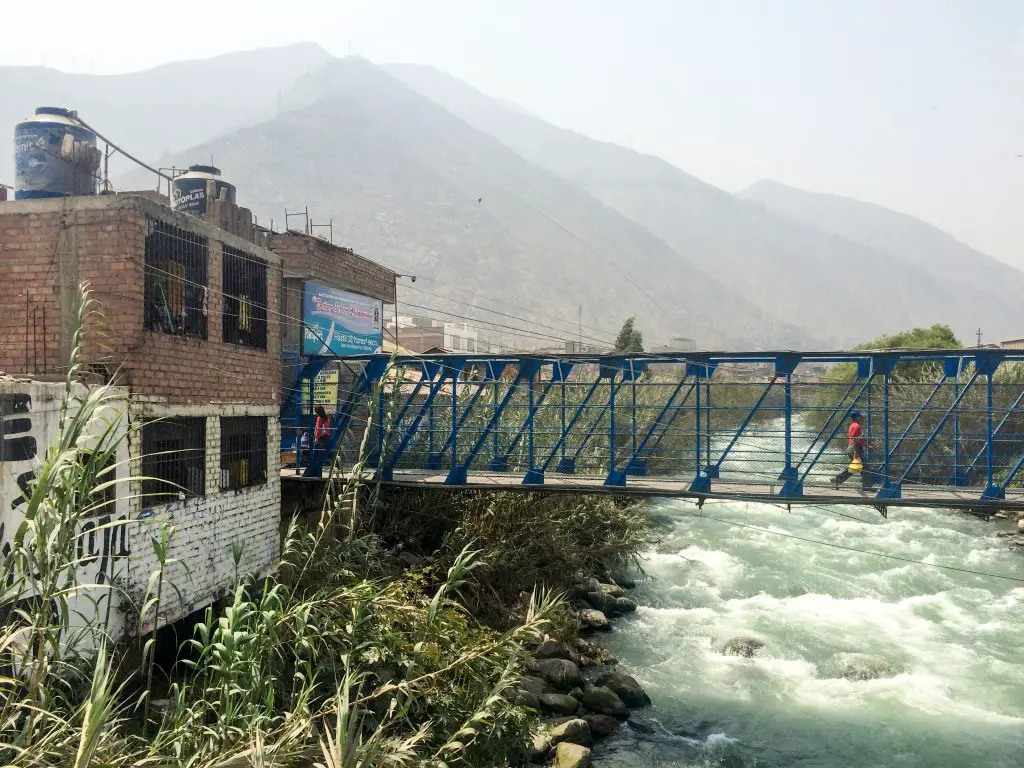 Local Peruvians cross a pedestrian bridge over the Rímac River in Chosica, Peru.