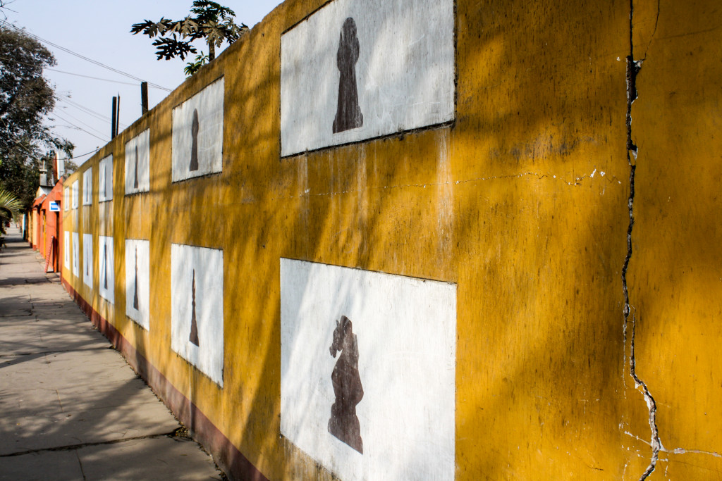 A yellow fence is painted with chess pieces in Chaclacayo, Peru | The Epicurean Traveler