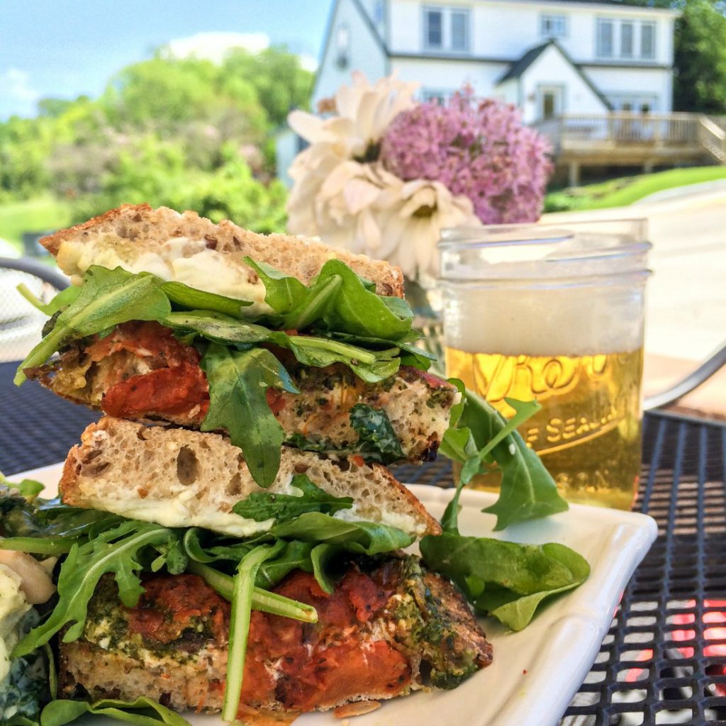 At Door County Creamery, my sandwich consisted of Door County Creamery fresh chevre, basil pesto, olive tapenade, tomato confit, and arugula. I paired it with a Door County Brewing Company's Pastoral, a Belgian farmhouse ale. (Erin Klema/The Epicurean Traveler)