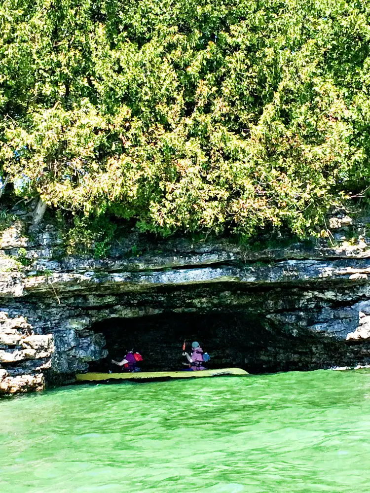 Kayakers paddle into a cave with Door County Kayak Tours