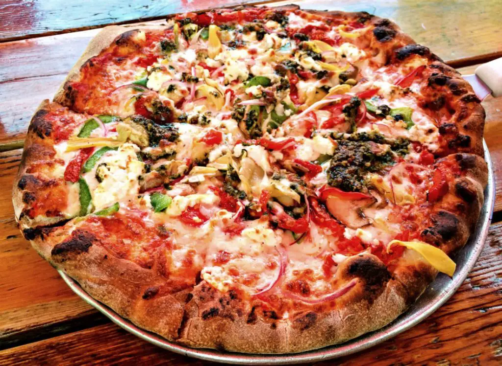 The veggie pizza is topped with red and green bell peppers, onions, mushrooms, artichoke hearts, sun dried tomatoes, pesto, Wisconsin goat cheese, and mozzarella at Wild Tomato in Fish Creek. (Erin Klema/The Epicurean Traveler)