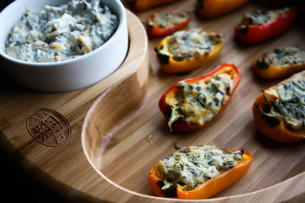 La Terra Fina dip-stuffed sweet peppers on an wooden serving tray with extra La Terra Fina dip