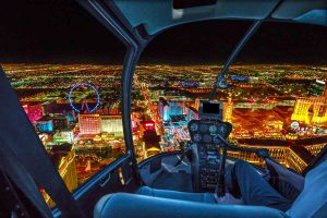View from helicopter interior of Las Vegas buildings and skyscrapers of downtown with illuminated casino hotels at night. Scenic flight above Vegas skyline by night in the Nevada United States of America.