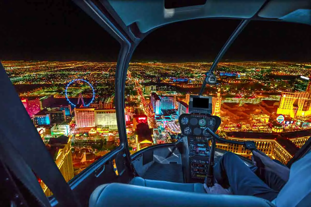 View from helicopter interior of Las Vegas buildings and skyscrapers of downtown with illuminated casino hotels at night. Scenic flight above Vegas skyline by night in the Nevada United States of America.