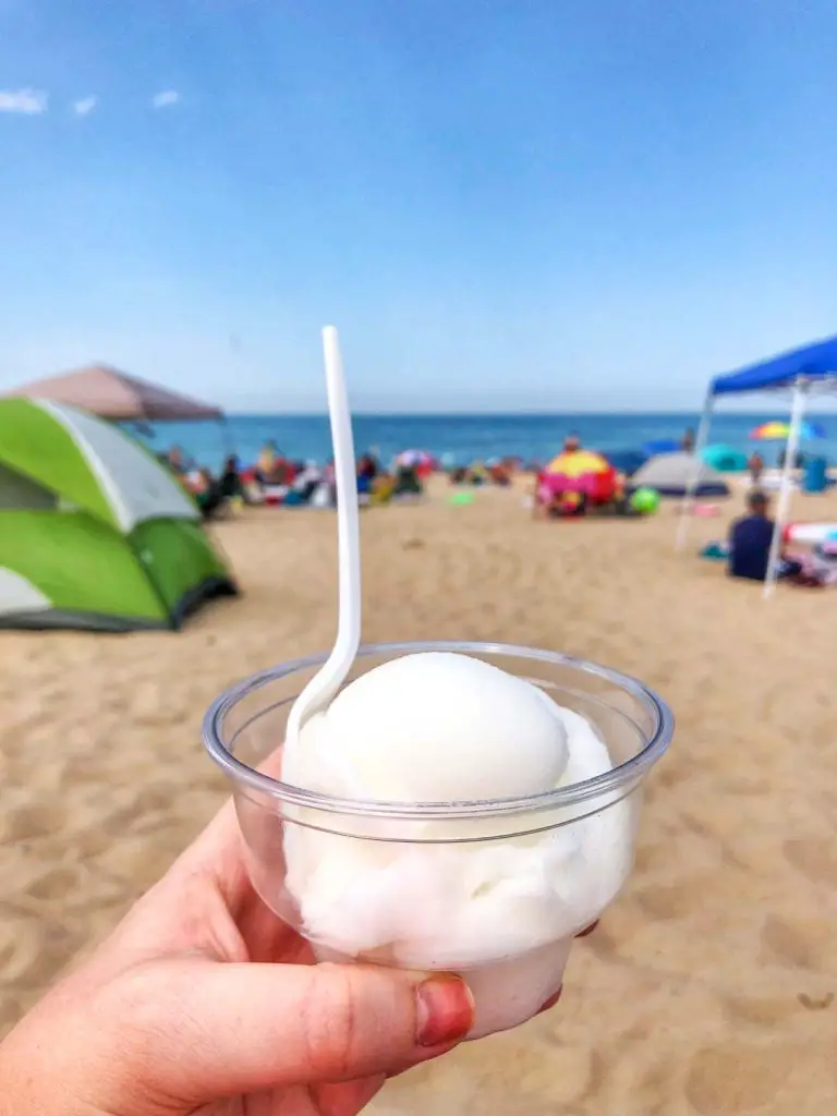 A woman's hand holds an Italian ice frozen treat during the summer at the Warren Dunes State Park beach in Sawyer, Michigan, USA