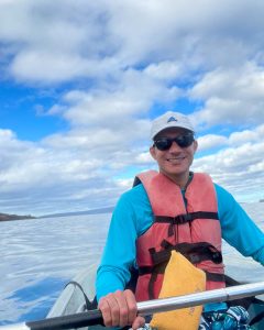 A male kayaker in Maui sports sun protection apparel, including a rash guard, hat, and sunglasses