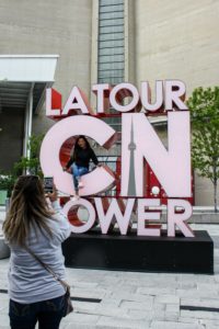 Tourists take photos with the CN Tower sign in Toronto, Ontario, Canada.