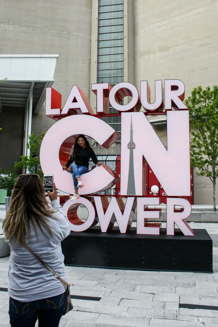 Tourists take photos with the CN Tower sign in Toronto, Ontario, Canada.