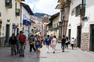 Travelers and locals walk down a street in Cusco, Peru.