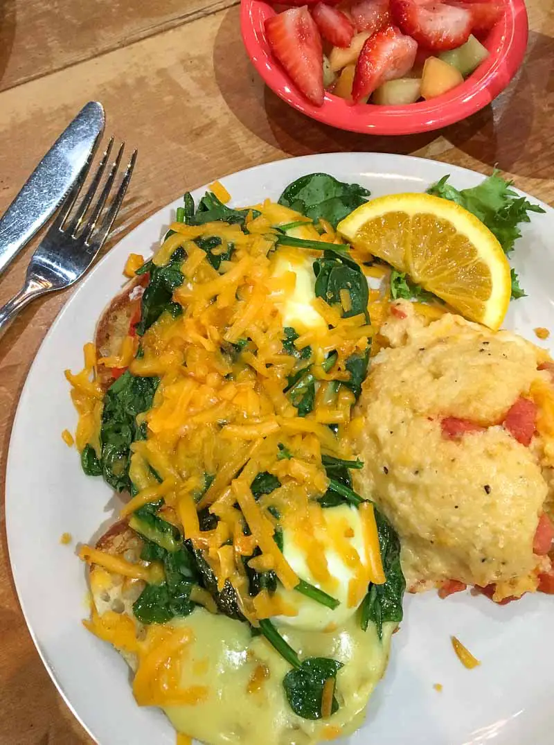 Breakfast of Florentine Eggs Benedict with tasty cheese grit casserole and a side of fresh fruit at Josie's in Lexington, Kentucky, USA