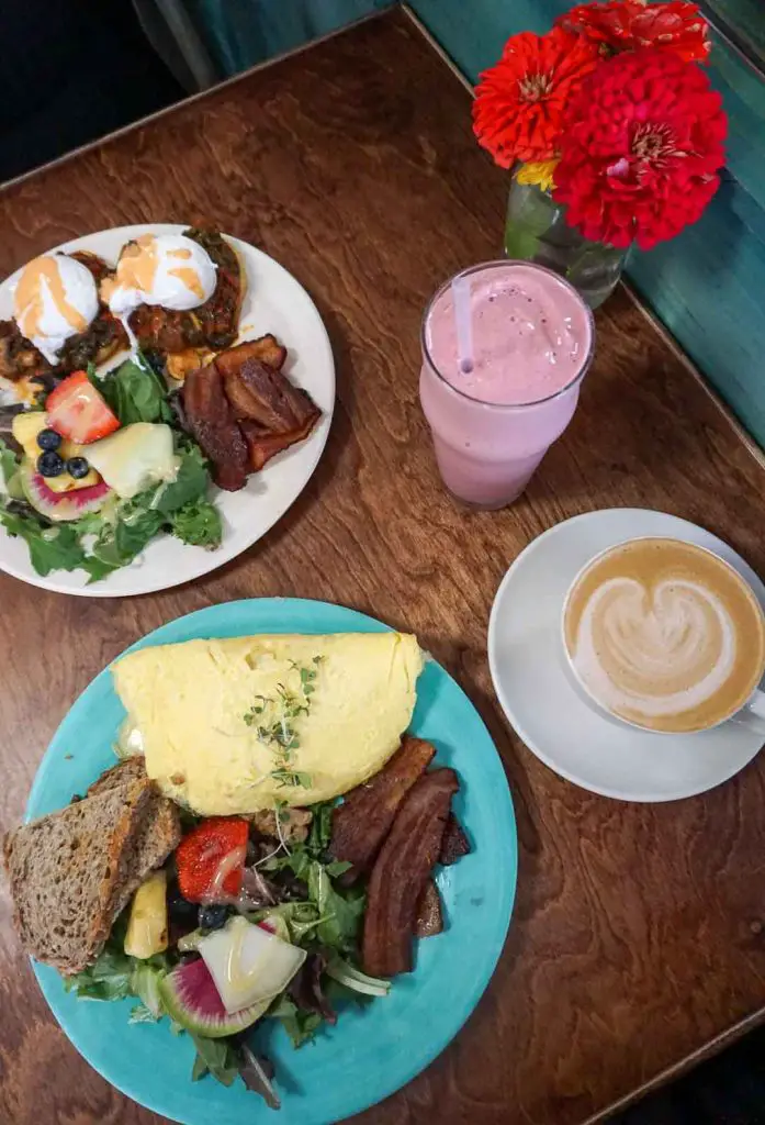 Breakfast spread of Eggs Benedict, an omelette, a smoothie, and a latte at health-food restaurant Juicy Kitchen in Ann Arbor, Michigan