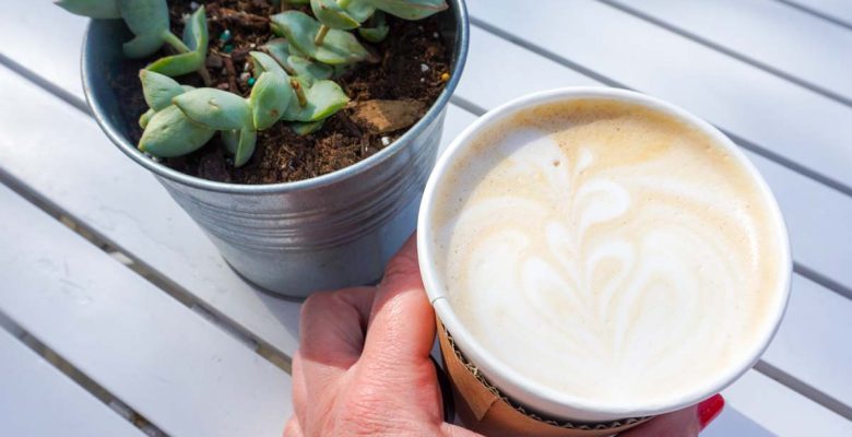 A woman's hand holds a lavender and honey latte outside an a coffee shop in Ann Arbor, Michigan