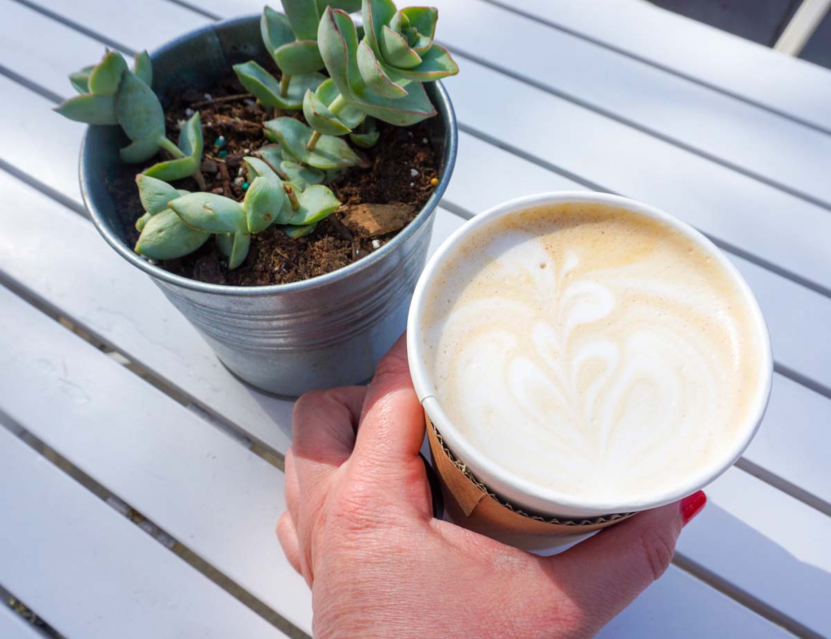A woman's hand holds a lavender and honey latte outside an a coffee shop in Ann Arbor, Michigan