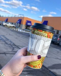 Zingerman's Coffee Company to-go coffee cup in a woman's manicured hand outside the Zingerman's Coffee Company warehouse and cafe in Ann Arbor, Michigan, USA