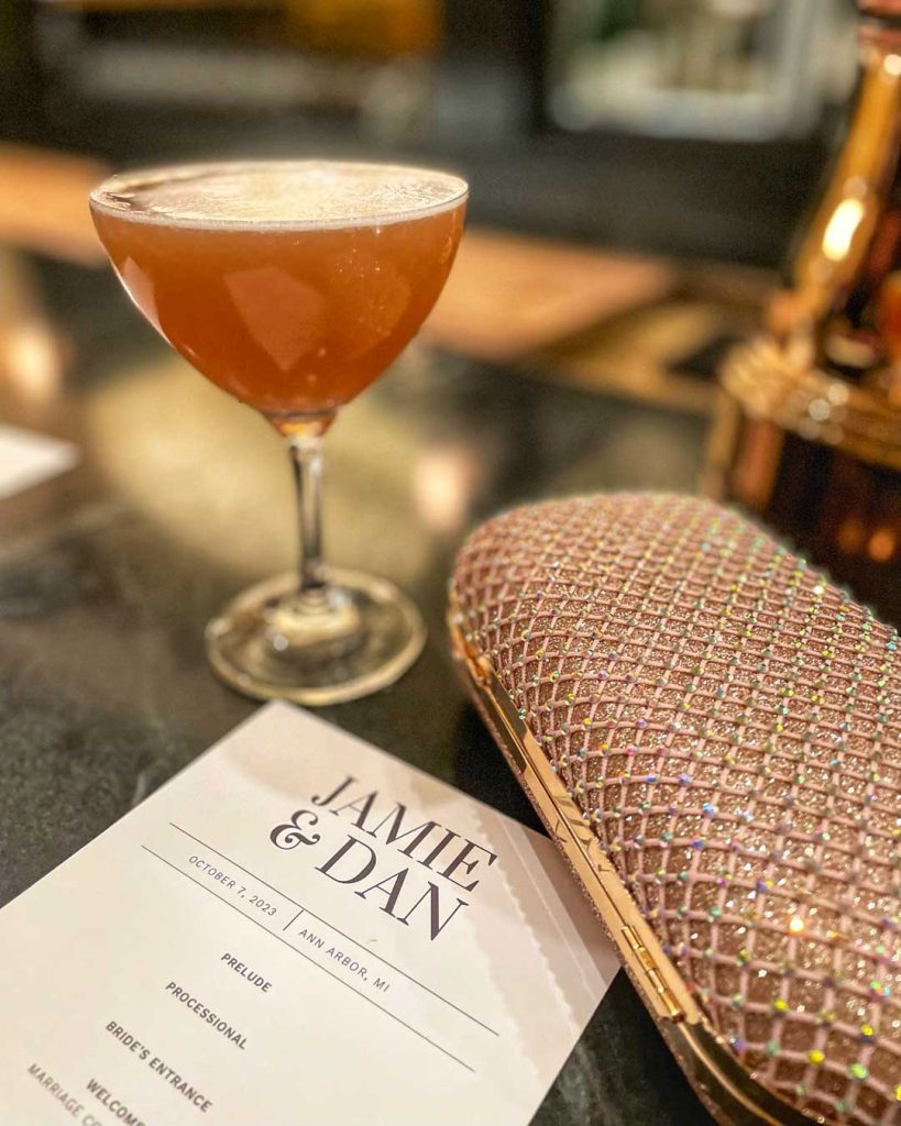 French martini, rose gold clutch purse, and wedding program sit on the bar of Weber's Restaurant in Ann Arbor, Michigan, USA