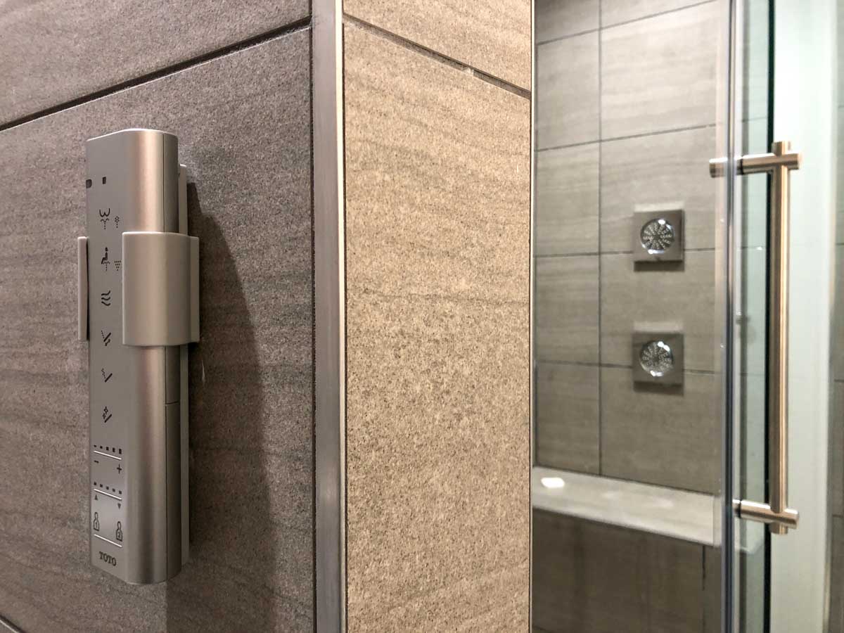 Guest bathroom with rainfall shower and Toto smart toilet remote control in a Deluxe King room at Weber's Boutique Hotel & Restaurant in Ann Arbor, Michigan, USA
