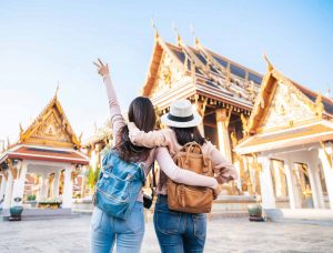 Two female friends face temple in Thailand with arms around each other