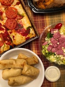 Buddy's Pizza carry-out meal with Detroit-style four-square pizza topped with tomato slices and green pepper, antipasto salad, and Buddy Bread with ranch dressing