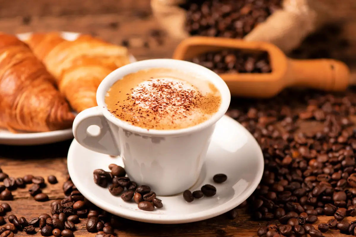A cup of cappuccino with coffee bean as background close up