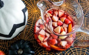 Overhead shot of Michigan Apple Cider Sangria in glass potbelly pitcher in Halloween table setting