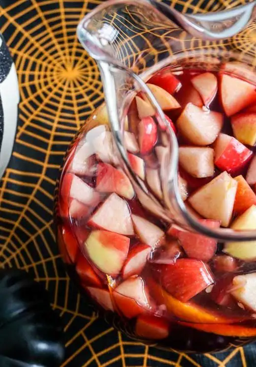 Overhead shot of Michigan Apple Cider Sangria in glass potbelly pitcher in Halloween table setting