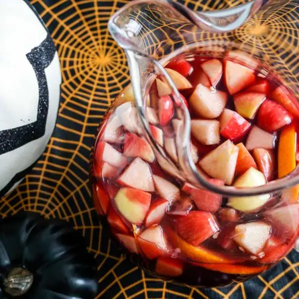 Overhead shot of Michigan Apple Cider Sangria in glass potbelly pitcher in Halloween table setting
