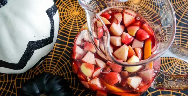 Overhead shot of Michigan Apple Cider Sangria in glass potbelly pitcher in Halloween table setting