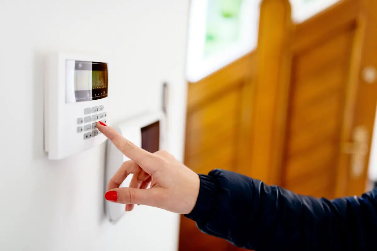 Young woman entering security code on home security alarm system keypad