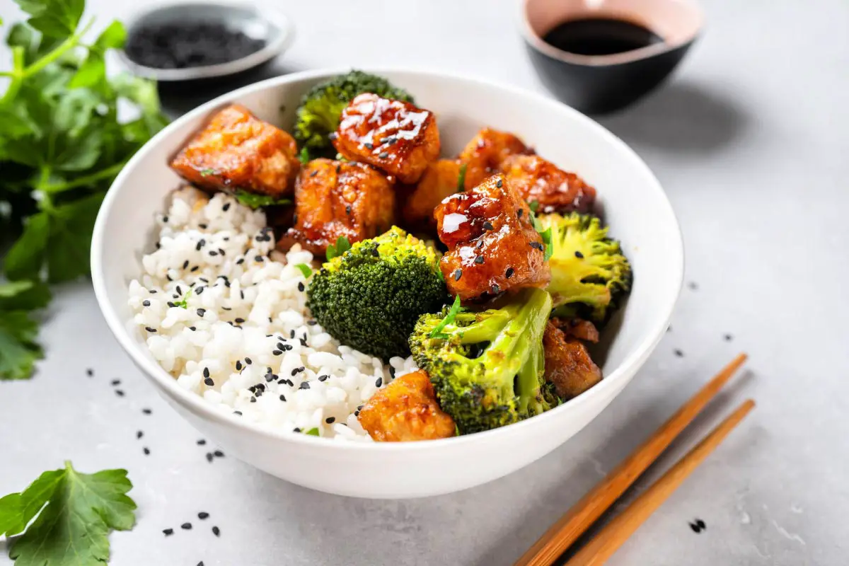 Healthy vegan home-cooked Asian meal of tofu, rice, and broccoli bowl with white background