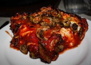 Chicago deep-dish pizza topped with mushrooms and green olives at Pequod's Pizza Lincoln Park in Chicago, Illinois, USA