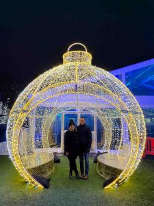 A couple poses inside an ornament-shaped holiday light installation at Beacon Park in Detroit
