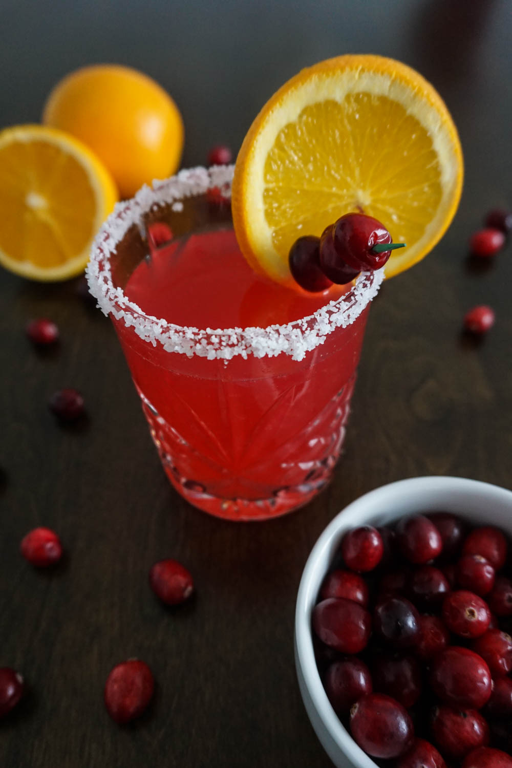 Cranberry Orange Margarita in Old Fashioned glass with oranges and fresh cranberry garnish