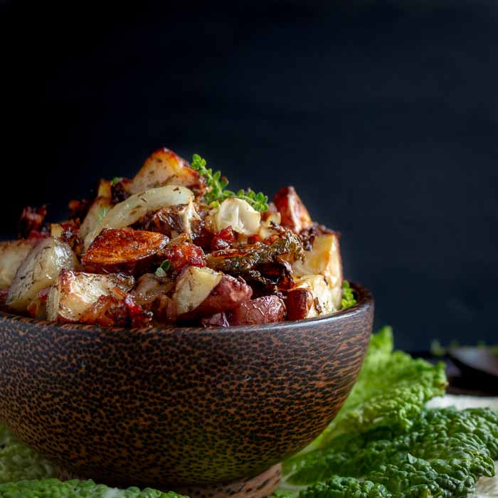 Bowl of roasted red potatoes and cabbage with black background