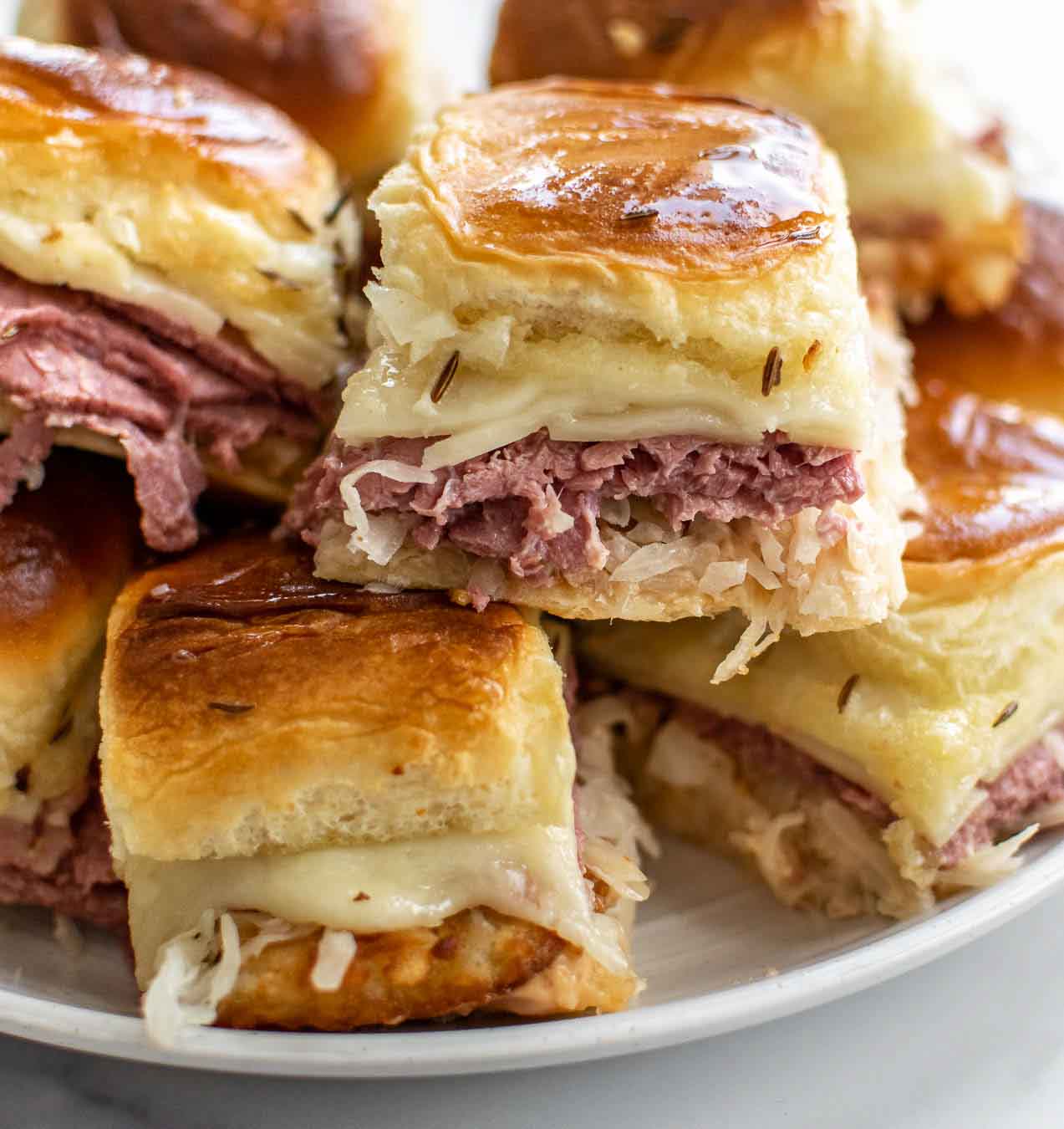 Corned beef sliders with hash browns stacked on white plate