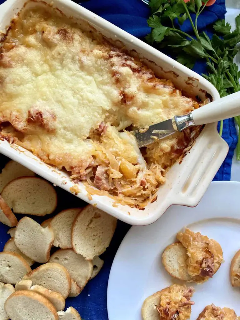 Baked Reuben dip in white baking dish and scooped onto baguette slices