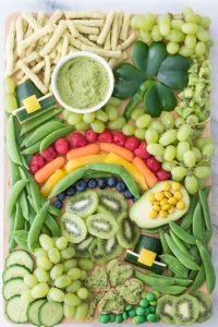 St. Patrick's Day snack board with rainbow-and-pot-of-gold mosaic made from fruits, veggies, and. other healthy vegan foods