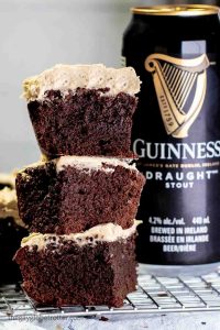 Stack of three Guinness brownies with espresso Guinness buttercream on cooling rack next to Guinness beer can