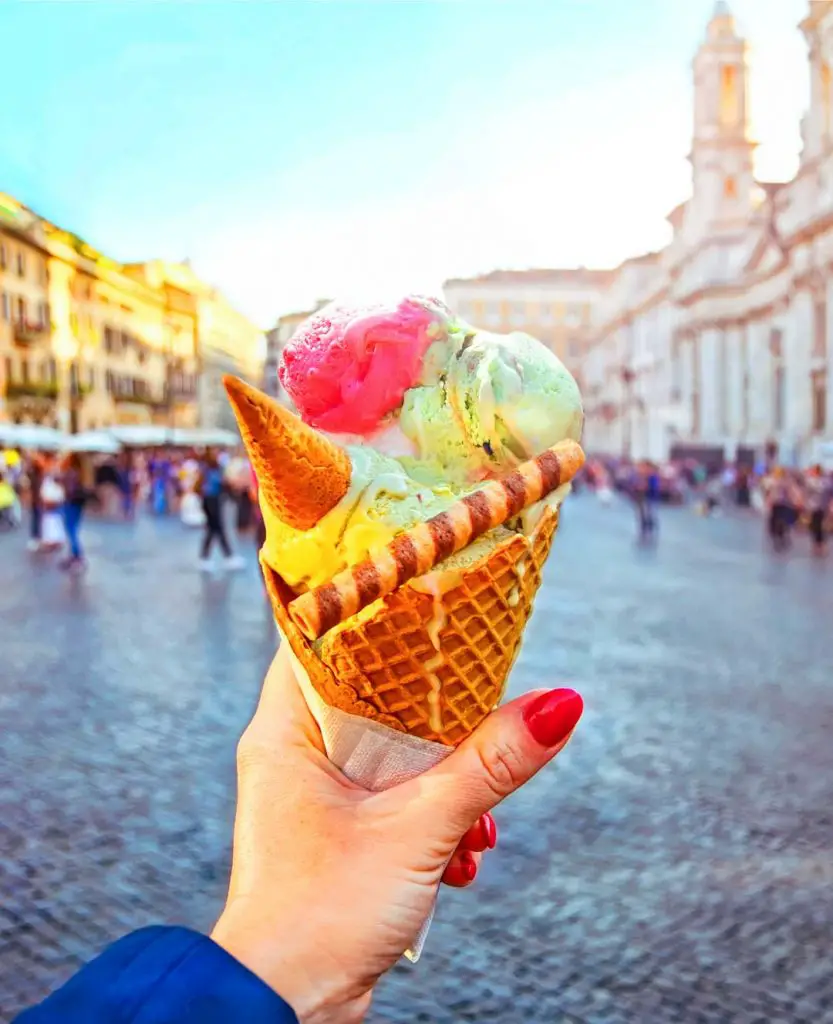 Italian ice cream cone held in hand on the background of Piazza Navona in Rome, Italy