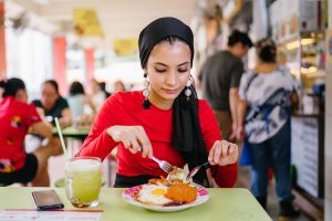 A woman eats nasi lemak at at hawker center in Singapore