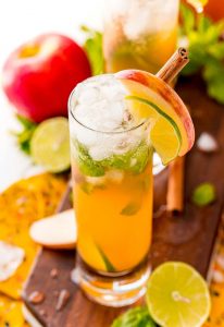 Apple cider mojito garnished with lime and apple slices and cinnamon stick