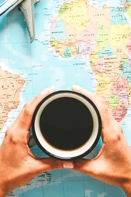 Gift ideas for coffee travelers banner image with a traveler holding a cup of coffee over a world map with travel gear around the map