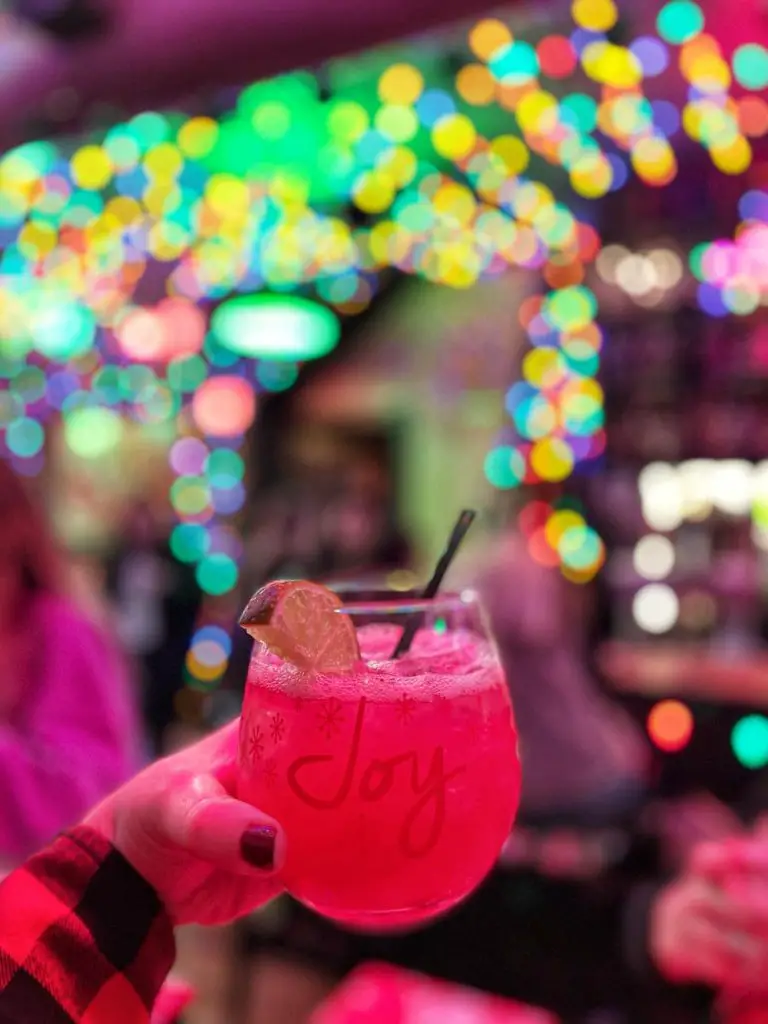 Woman holds a festive Jingle Juice holiday cocktail at the Christmas-themed Jingle popup bar at Ale Mary's Beer Hall in Royal Oak, Michigan