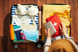 Overhead view of woman packing health essentials for travel into a suitcase