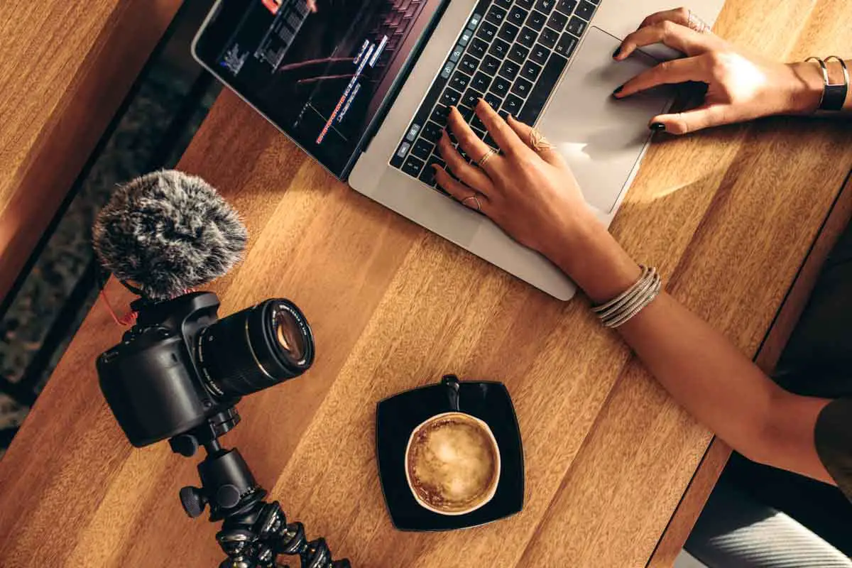 A female travel vlogger edits video on a laptop computer