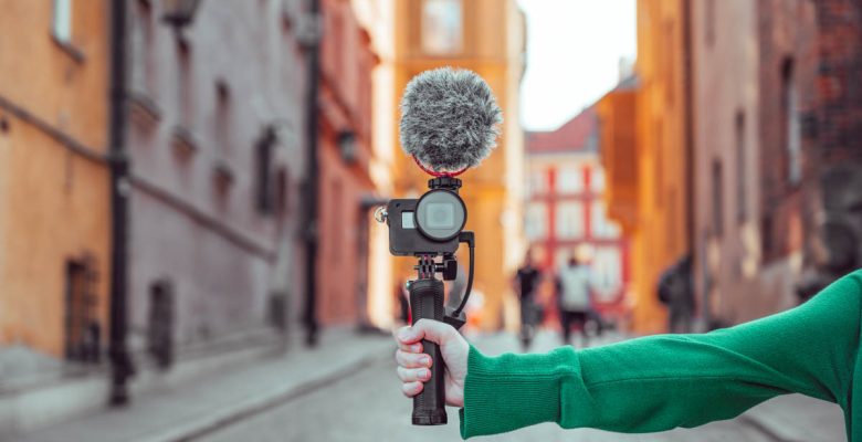 Travel vlogger holds camera with microphone to record a travel vlog