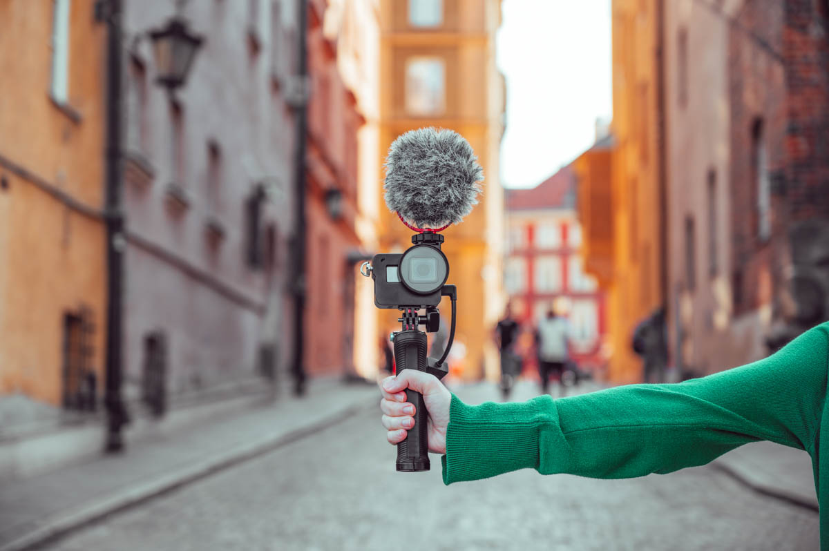 Travel vlogger holds camera with microphone to record a travel vlog