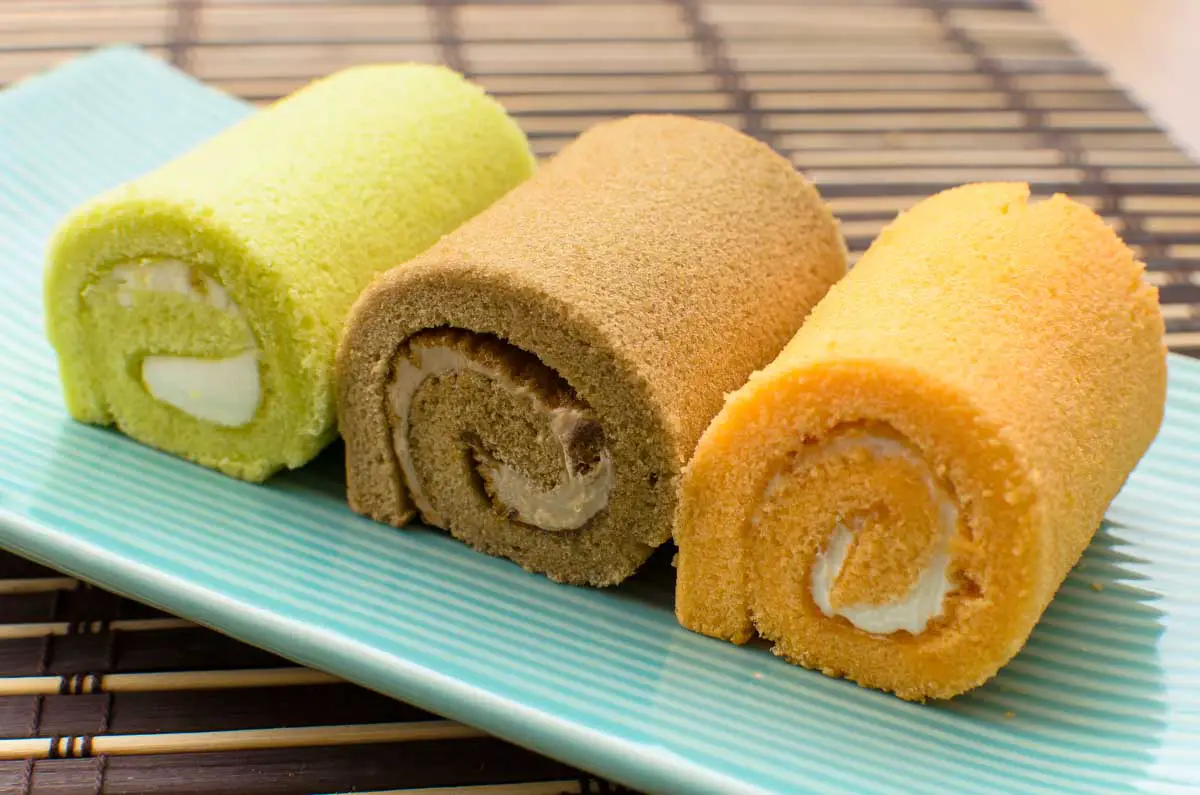 Colorful swiss rolls on a teal dish atop a bamboo mat