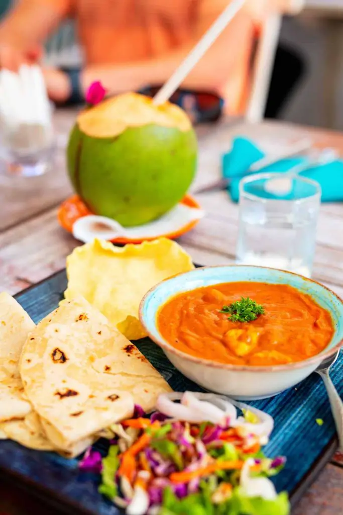 Mas roshi, also known as Maldivian fish curry, with roshi, a traditional flatbread, at a restaurant with a coconut to drink in the background