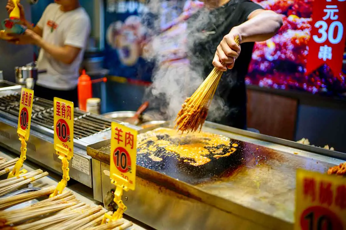 A local food stall grills snacks along a shopping street in Shenzhen, Guangdong, China